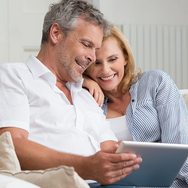 Adult couple looking into their tablet and smiling 